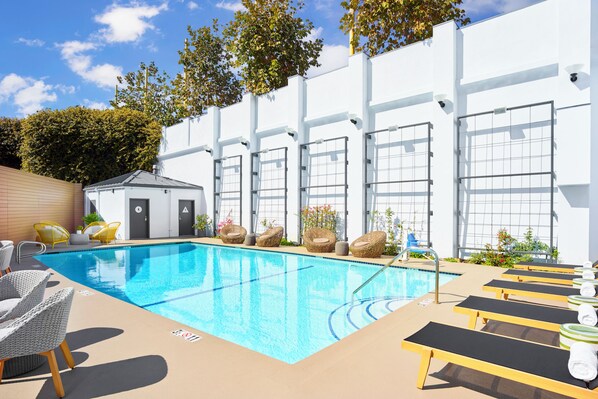 A swimming pool with lounge chairs and a small building, likely a changing room or storage. - The Pierside (Santa Monica)