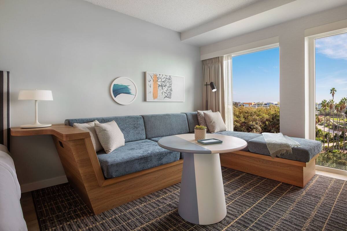 A modern hotel room with a sofa, a round table, and artwork on the walls.