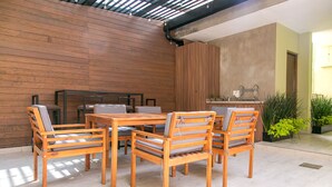 A wooden dining table with six chairs, a kitchen area with a sink and countertop, and a wooden wall. - Noma Condesa Mexico City by Lumina (Mexico City)