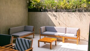 A patio area with wooden furniture, including sofas and a table, and a string of lights. - Noma Condesa Mexico City by Lumina (Mexico City)