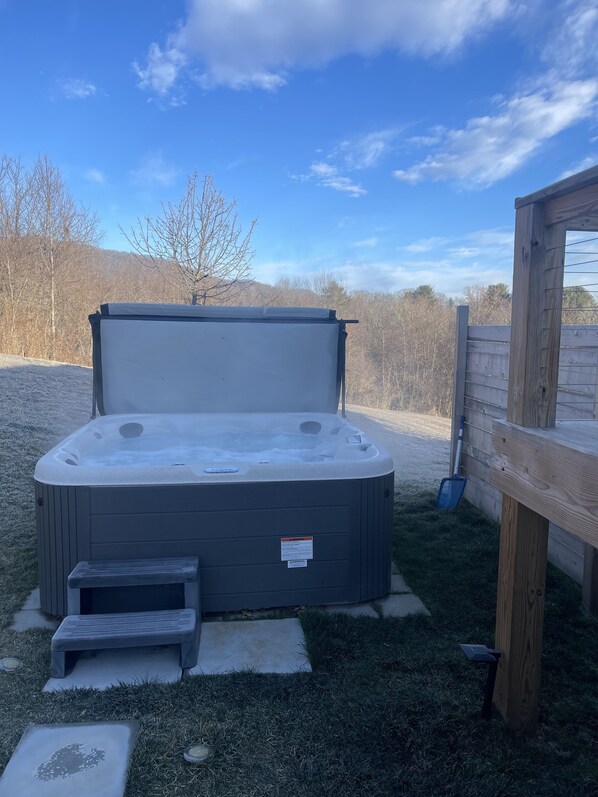 A hot tub with a wooden deck and a wooden fence in the background. - Beautiful home, walk into downtown, hot tub, dog friendly, Huge yard, fire pits. (Waynesville)