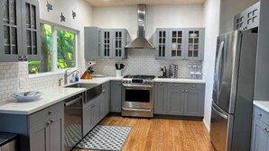Una cocina moderna con armarios grises, electrodomésticos de acero inoxidable y suelo de madera.
