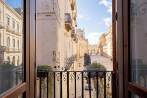 Vista desde un balcón sobre una calle estrecha flanqueada por edificios.