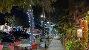 A nighttime outdoor seating area with tables and chairs, a sidewalk, and decorative string lights. - Waterfront Marina District  Luxury Home & In-law Suite (Gulfport)