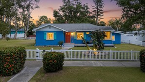 A single-story house with a blue exterior, a front porch, and a white picket fence. - Waterfront Marina District  Luxury Home & In-law Suite (Gulfport)