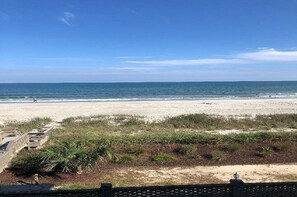 A beach with a clear sky, a sandy shore, and some vegetation in the foreground. - Ocean Front, 2nd Floor Unit with Balcony, 2 Bedroom Sleeps Six (Surfside Beach)