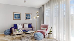 Una sala de estar con sofá, sillón, mesa de centro y cojines decorativos.
