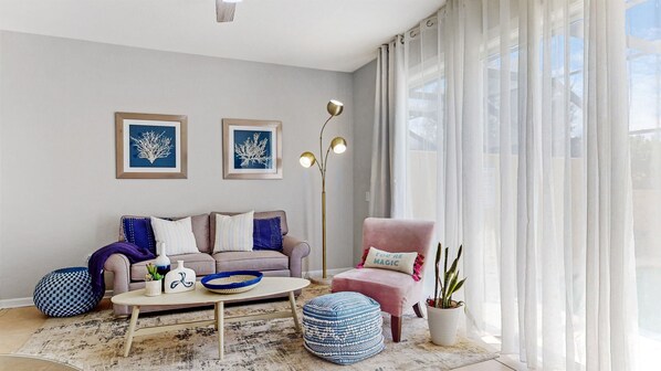 Una sala de estar con sofá, sillón, mesa de centro y cojines decorativos.