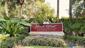 Een bordje voor Island Retreat Condominium, omringd door weelderige begroeiing.