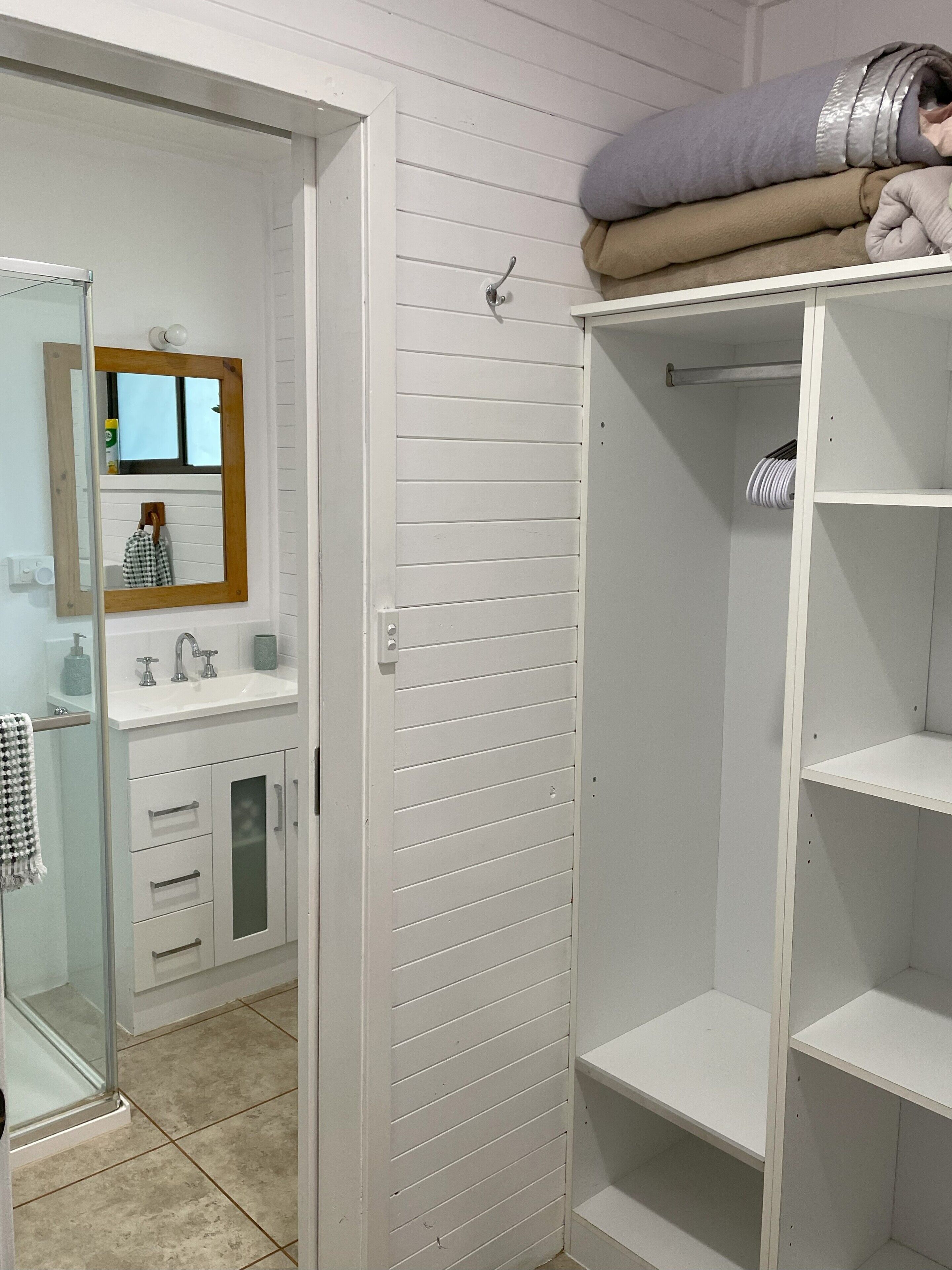 A bathroom with a white vanity, a mirror, a sink, and a towel rack.