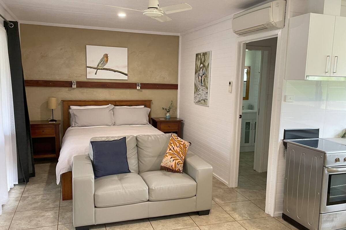 Une chambre à coucher comprenant un lit, un canapé, une table de chevet, un ventilateur de plafond et un appareil de climatisation.