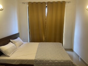A neatly made bed with white linens and a patterned throw blanket.