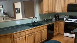 A kitchen with wooden cabinets, a black stove, and a dishwasher. - Remodeled beautiful farmhouse with stunning lake view (Honeoye)