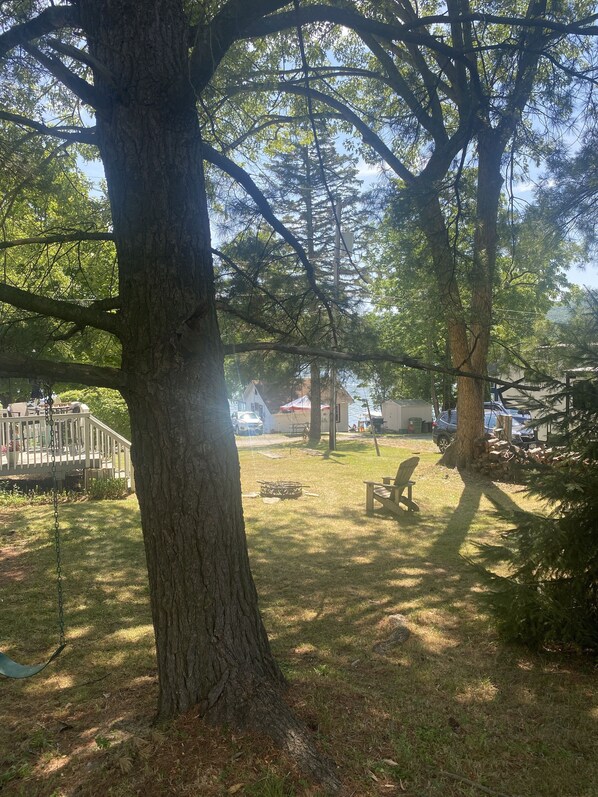 A backyard with a swing set, a fire pit, and a picnic table.