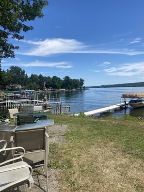 A lakeside patio with outdoor seating and a dock extending into the water.