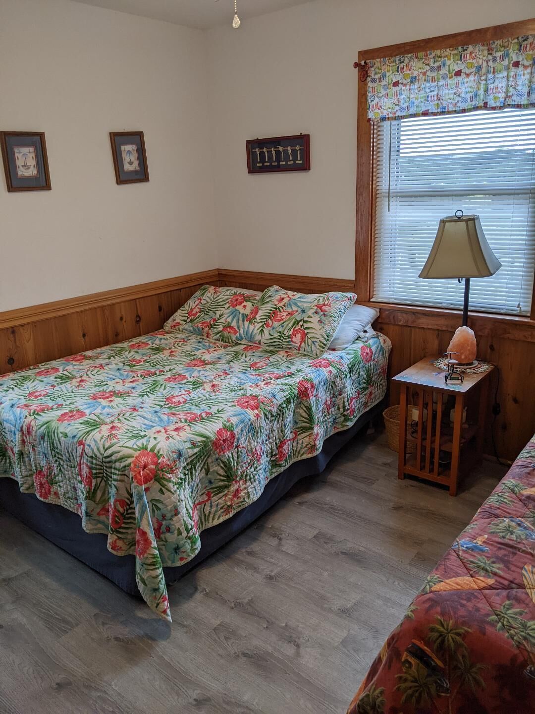 Une chambre à coucher avec un lit en bois, une petite table de chevet avec une lampe et une fenêtre avec des stores.