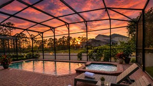 Uma área de piscina com hidromassagem, espreguiçadeiras e uma estrutura de pérgola.