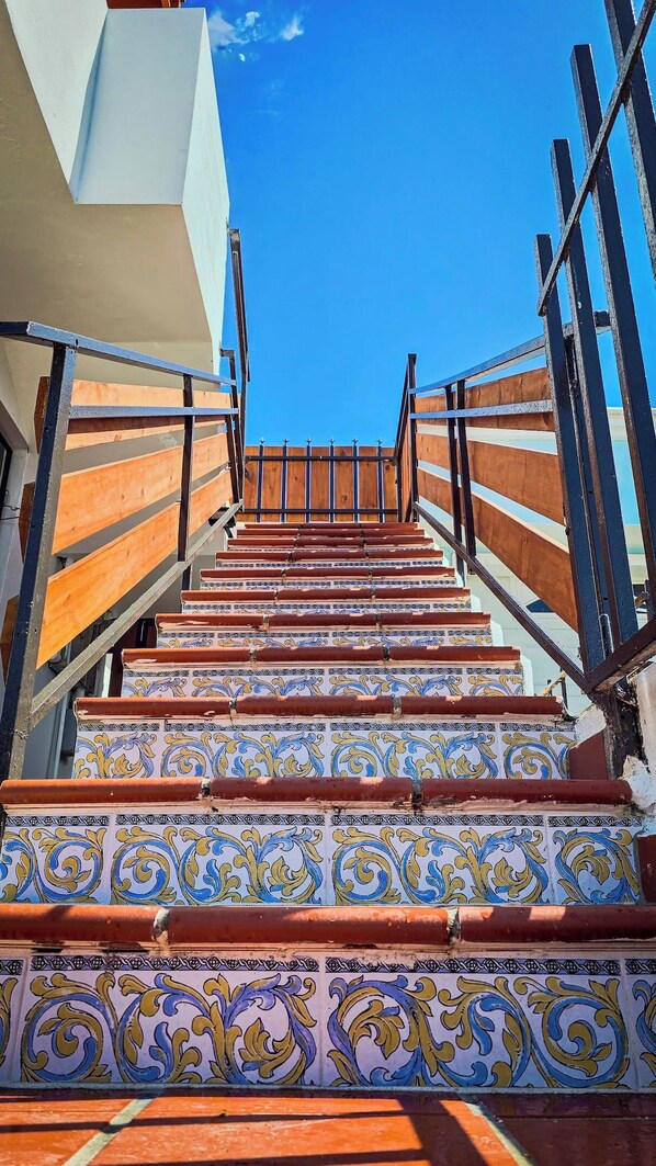 A staircase with ornate tile patterns leading upwards, flanked by metal railings.