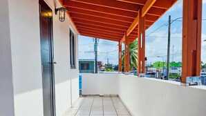 A covered outdoor corridor with tiled flooring, a metal door, and a view of the cityscape in the background. - Stunning 2 BR Private Apartment with Parking (Carolina)