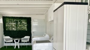 A compact kitchen with a washing machine, a refrigerator, and a small dining area with two chairs and a table. - Stunning 2 BR Private Apartment with Parking (Carolina)