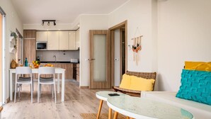 A modern kitchen with white cabinets, a microwave, and a dining area with a table and chairs. - Bright Apartment with Pool in Portimão | 5 Min Walk to the Beach by Lisbeyond (Portimão)