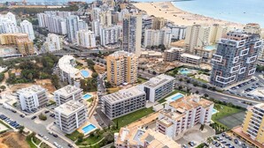 A coastal residential area with high-rise buildings, a beach, and a marina. - Bright Apartment with Pool in Portimão | 5 Min Walk to the Beach by Lisbeyond (Portimão)
