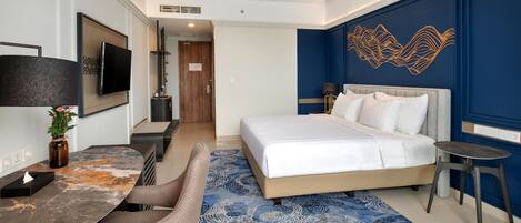 Quarto de hotel moderno com uma cama grande, uma escrivaninha com cadeira, televisão de tela plana e um painel decorativo na parede.