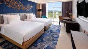 Habitación de hotel con dos camas, un escritorio, una silla, un televisor y vistas al exterior.