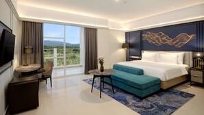 Habitación de hotel moderna con una cama grande, un escritorio, una silla y vistas al exterior.