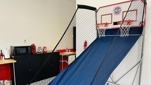 Een basketbalveld met een blauwe glijbaan, een basketbalring en een rode brandblusser.