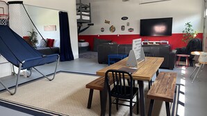 Een moderne woonkamer met een bank, een blauwe fauteuil, een houten tafel en een televisie.