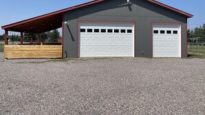 Een tweemaal garage, grenzend aan een gebouw met een rood dak en een overdekt gebied met houten banken.