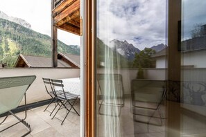 A balcony with a view of mountains, a glass door, and outdoor furniture. - Casa Ami with wonderful mountain view (Moso)
