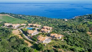An aerial view of a coastal residential area with houses arranged in rows, a swimming pool, and a clear view of the sea. - Casa del Mare Blu - Seaview apartment with pool (Tertenia)