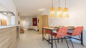 A modern kitchen with a dining area, featuring a wooden countertop, a dining table with red chairs, and three hanging wicker pendant lights. - C'est la vue - Seaview apartment with pool (Marina, Tertenia)