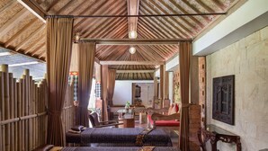 A traditional room with a bamboo wall, a wooden ceiling, and a bed with a patterned bedspread. - Kailash Suites Ubud (Sukawati)