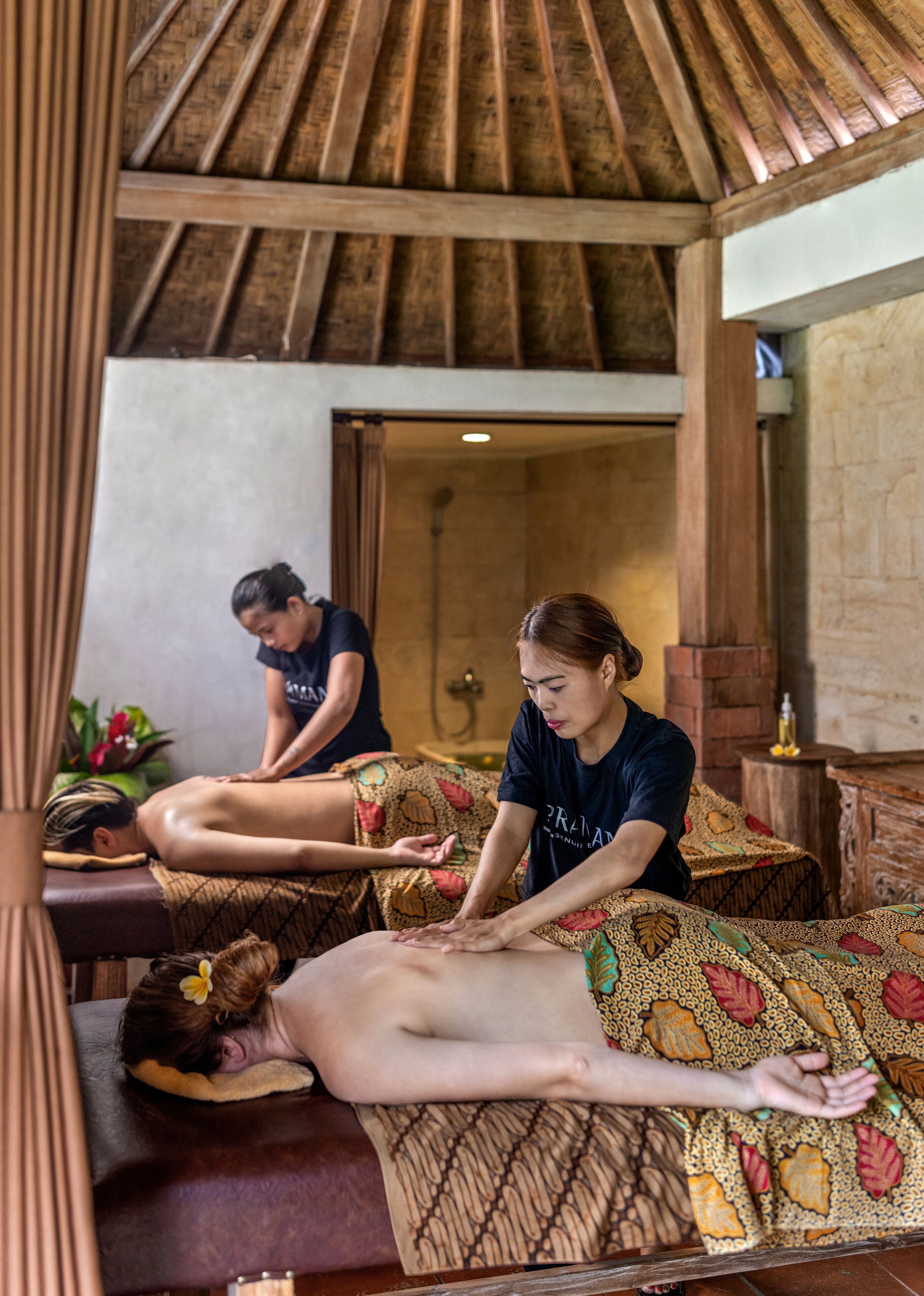 Une salle de massage avec des poutres en bois au plafond, une table de massage et une personne qui reçoit un massage.