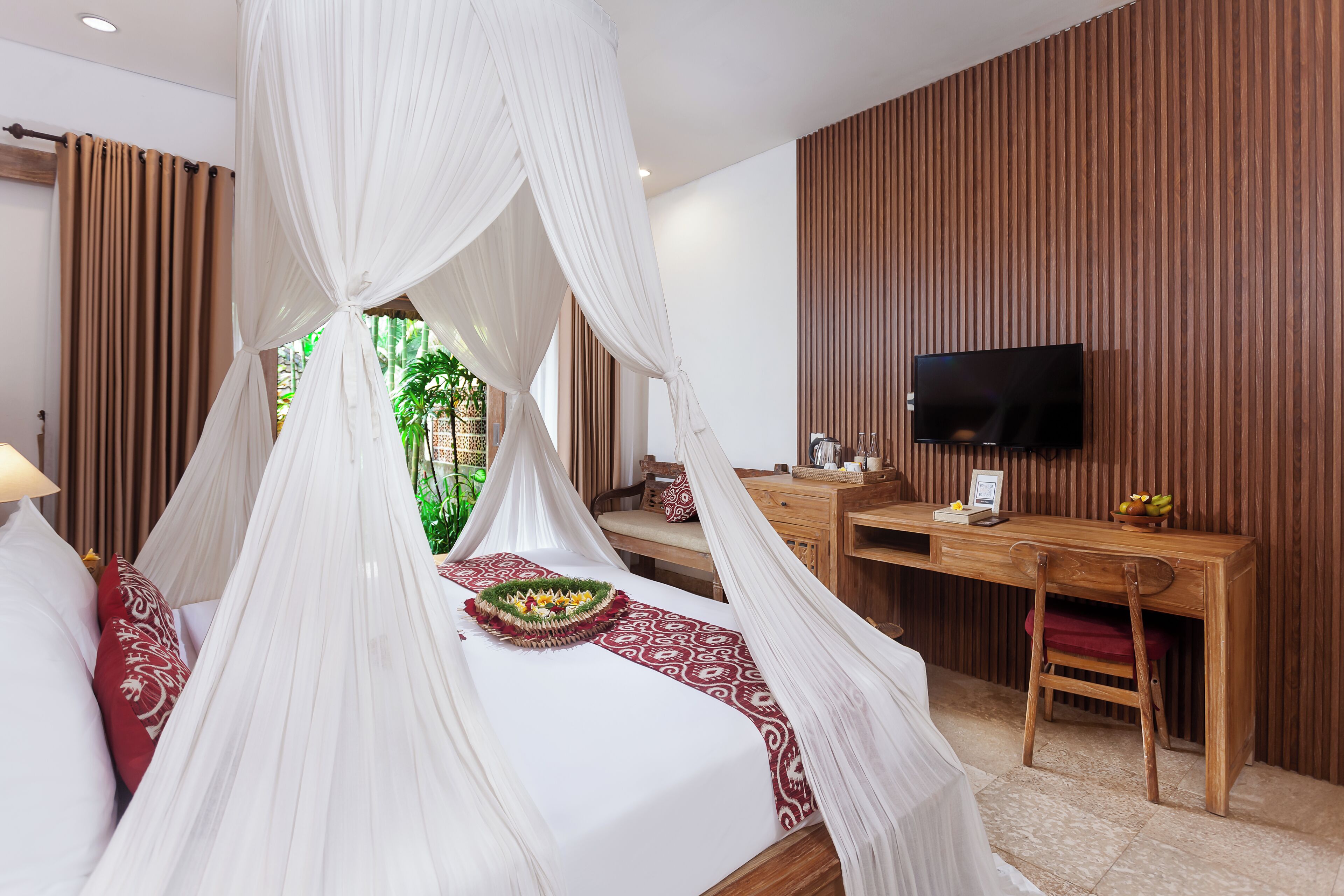 Un dormitorio con cama con dosel, un escritorio, un televisor y vistas a zonas verdes.