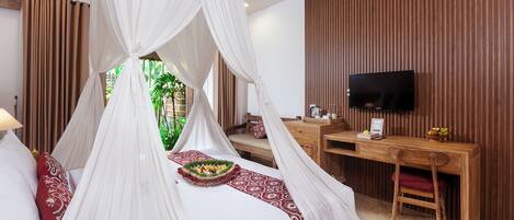 Un dormitorio con cama con dosel, un escritorio, un televisor y vistas a zonas verdes.