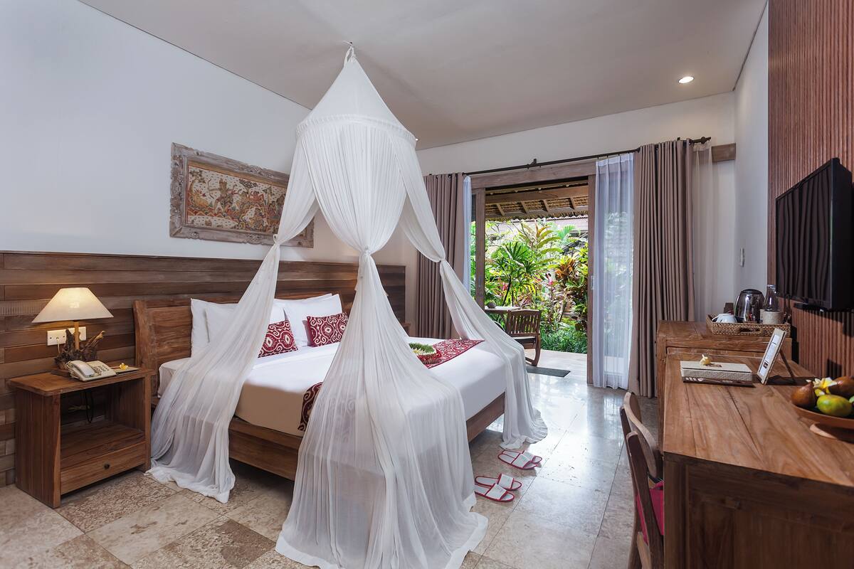 Una habitación de hotel con cama, mesita de noche, escritorio y televisor.