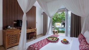A bedroom with a bed, a desk, and a view of an outdoor pool. - Kailash Suites Ubud (Sukawati)