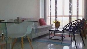 Una sala de estar moderna con una mesa de centro de vidrio, un sofá y una butaca.