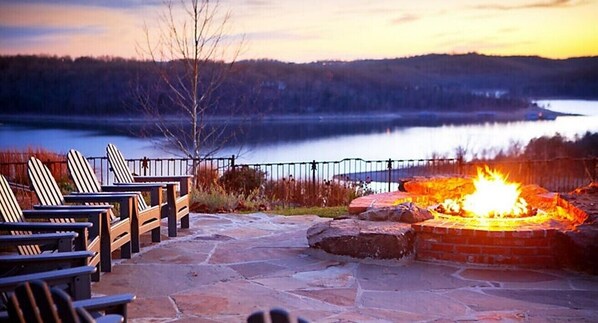 Sit by the fire pit in a serene lakeside setting surrounded by Adirondack chairs.