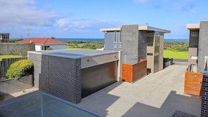 Un edificio residencial moderno con garaje, piscina y vistas al océano.