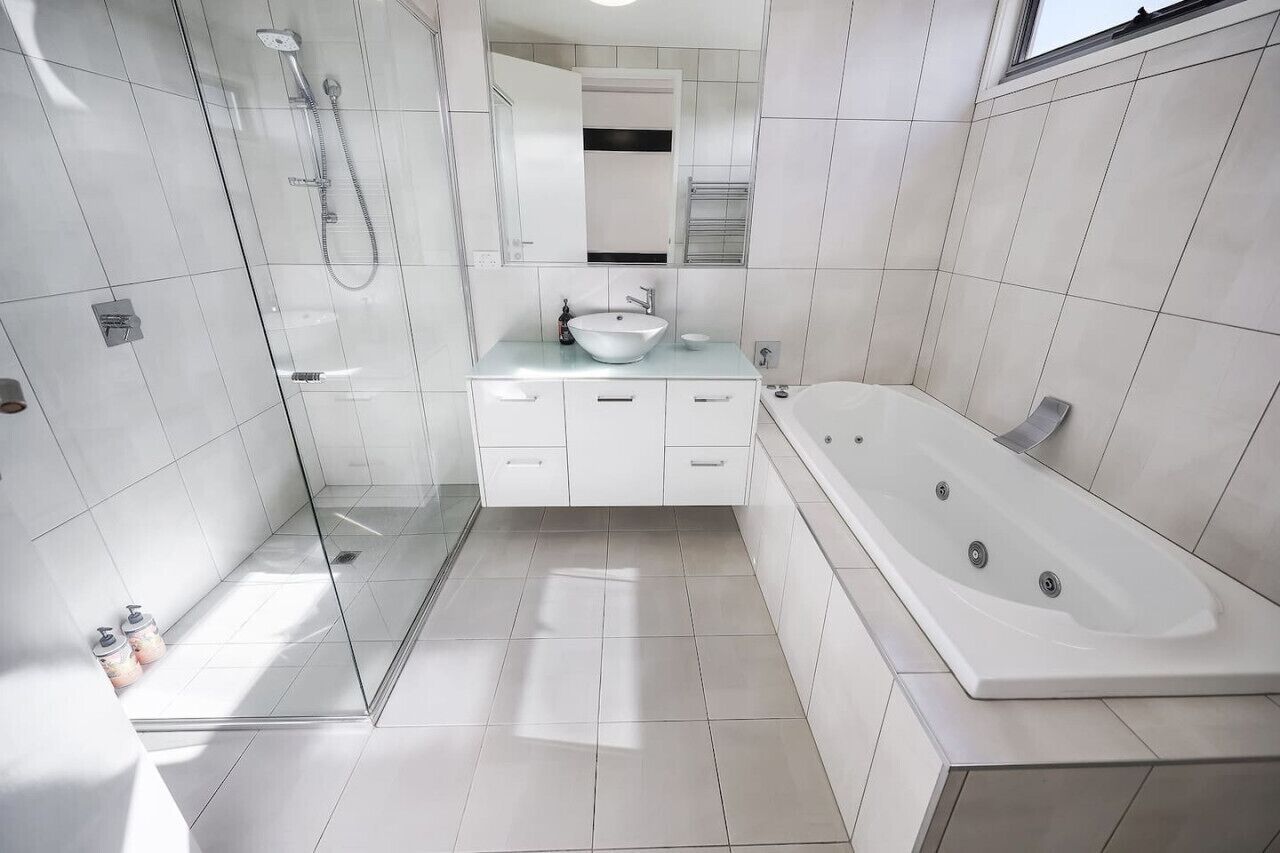 A modern bathroom with a glass-enclosed shower, a freestanding bathtub, and a vanity with a sink and mirror.