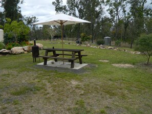 A picnic table with a canopy, surrounded by a grassy area with trees and rocks. - Cherry Mango Guesthouse (Kullogum)