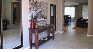 Un salon avec une console en bois foncé, une grande peinture abstraite et un coin repas comprenant des chaises et une table.