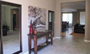 Una sala de estar con un aparador de madera oscura, un cuadro abstracto grande y un comedor con sillas y una mesa.