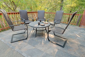 An outdoor patio with a round table and six chairs, surrounded by a wooden fence and trees. - Rogue Keystone Lodge/Epic River Views/Sleeps 7/SPA (Gold Beach)