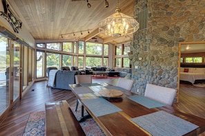A spacious living area with a stone wall, large windows, and a wooden ceiling.